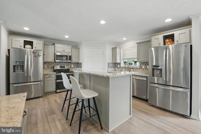  - kitchen featuring stainless steel appliances, light wood-style flooring, open shelves, crown molding, and a center island