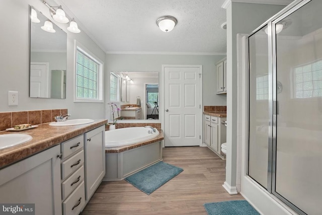  - ensuite bathroom featuring a stall shower, a bath, double vanity, wood finished floors, and crown molding