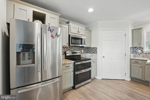  - kitchen with appliances with stainless steel finishes, ornamental molding, backsplash, light wood finished floors, and light stone counters