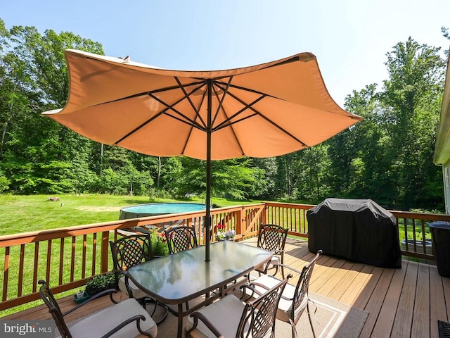  - wooden terrace featuring outdoor dining space, a lawn, grilling area, a pool, and view of scattered trees