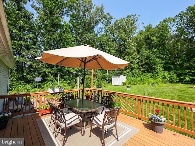  - wooden deck featuring a storage shed, outdoor dining space, and a yard