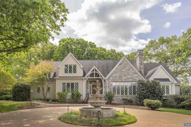 view of front of property with a chimney, stucco siding, and stone siding