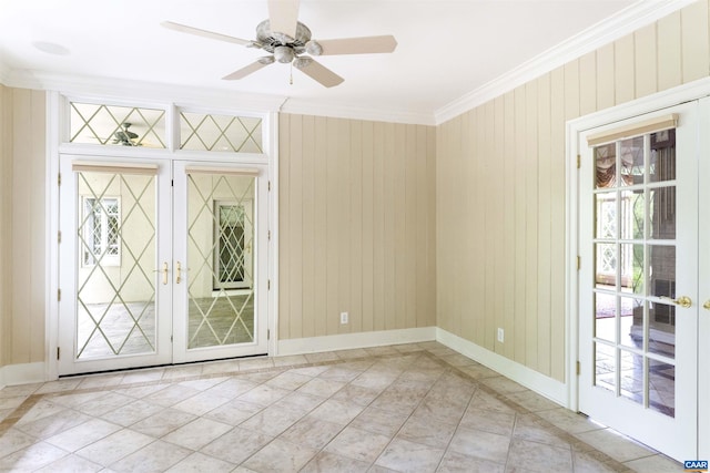 spare room with french doors, ornamental molding, baseboards, ceiling fan, and wood walls