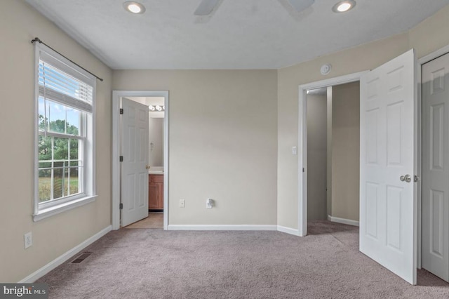 unfurnished bedroom featuring carpet flooring, recessed lighting, baseboards, ensuite bath, and ceiling fan