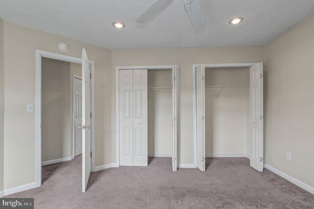 unfurnished bedroom with two closets, carpet, baseboards, and recessed lighting