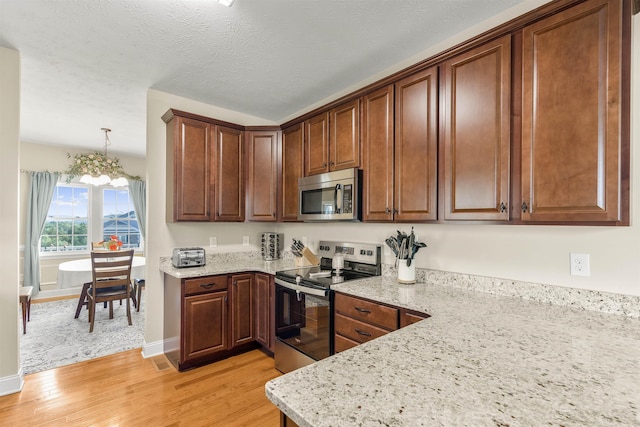 109 Beauregard Dr, Staunton, VA 24401 - kitchen featuring appliances with stainless steel finishes, light wood finished floors, a chandelier, and light stone counters