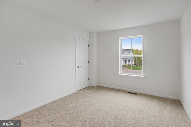 unfurnished room featuring light colored carpet and baseboards