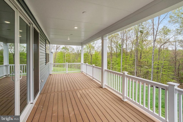 deck featuring covered porch and a wooded view