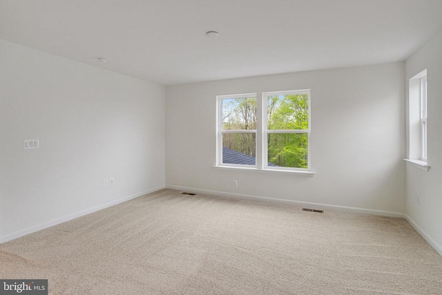 carpeted spare room featuring plenty of natural light and baseboards