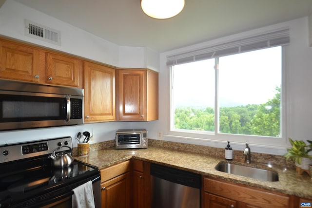 1606 Monticello Ave Unit G, Charlottesville, VA 22902 - kitchen featuring appliances with stainless steel finishes, brown cabinets, and light stone countertops