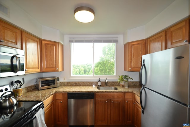 1606 Monticello Ave Unit G, Charlottesville, VA 22902 - kitchen with appliances with stainless steel finishes, brown cabinetry, and light stone counters