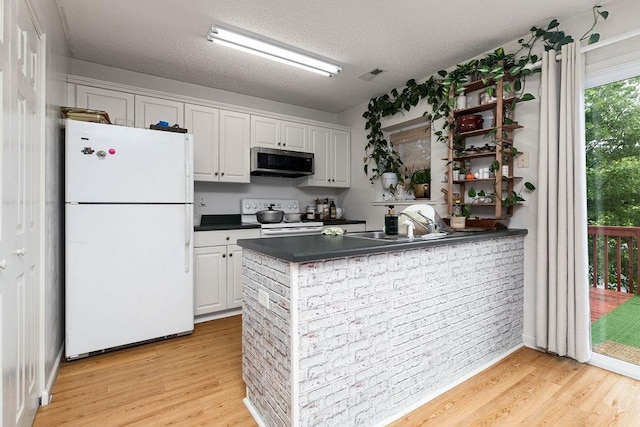 2387 King Arthurs Ct, Harrisonburg, VA 22801 - kitchen with white appliances, dark countertops, light wood finished floors, a sink, and a textured ceiling