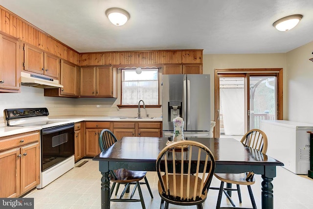 kitchen with a sink, stainless steel refrigerator with ice dispenser, electric stove, under cabinet range hood, and light countertops