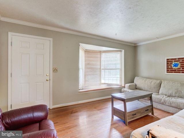 living area featuring crown molding, a textured ceiling, baseboards, and wood finished floors