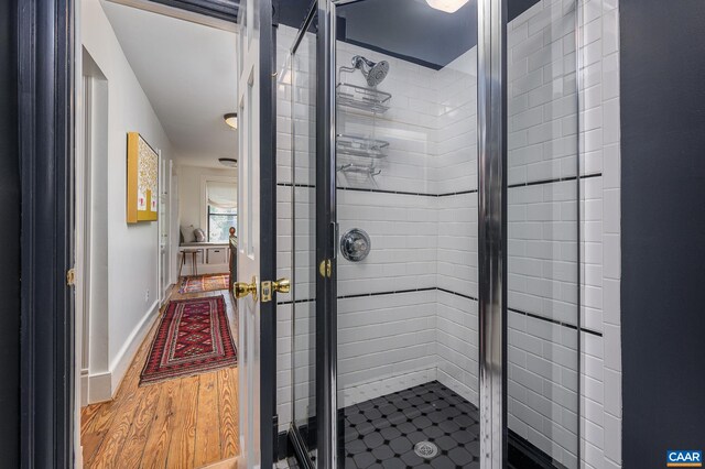 full bath featuring a stall shower, wood finished floors, and baseboards