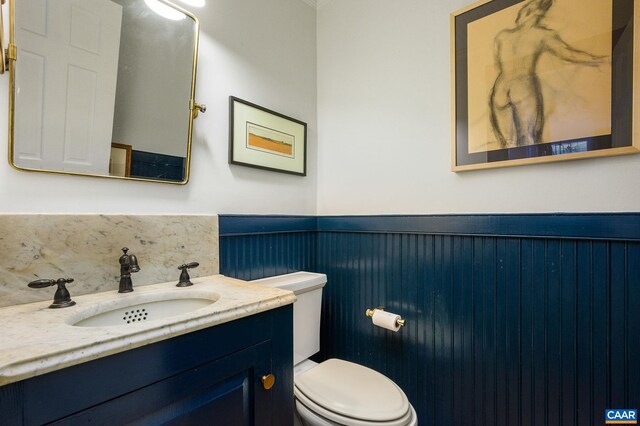 bathroom featuring a wainscoted wall, toilet, and vanity