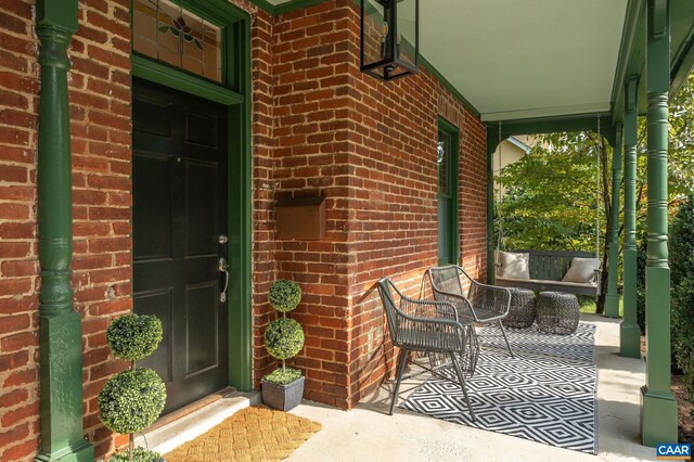 property entrance with covered porch and brick siding