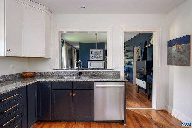 kitchen featuring dishwasher, a sink, white cabinets, and light wood-style flooring