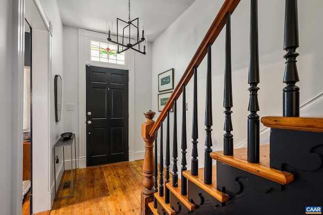 entrance foyer featuring a chandelier, hardwood / wood-style flooring, stairway, and baseboards