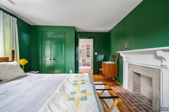 bedroom with a closet, wood finished floors, a fireplace, and baseboards