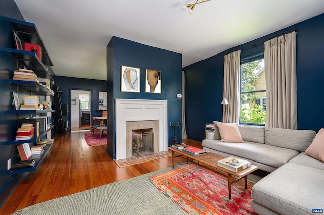 living area featuring wood finished floors, a tile fireplace, and baseboards