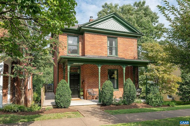 view of front of home featuring brick siding and a porch