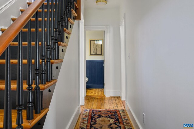 corridor featuring baseboards, hardwood / wood-style flooring, and stairs