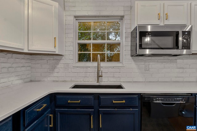 kitchen featuring black dishwasher, blue cabinets, a sink, stainless steel microwave, and decorative backsplash