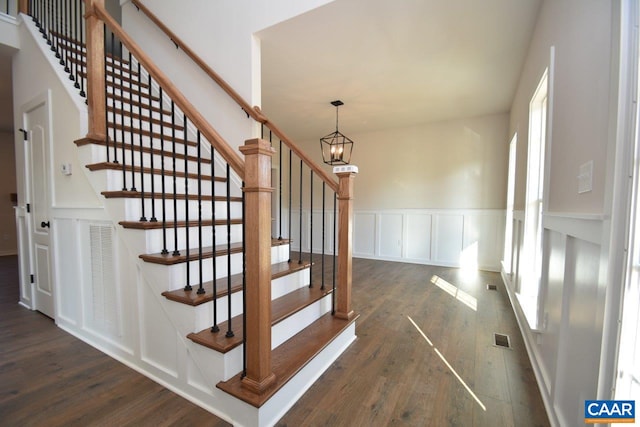stairway featuring visible vents, a decorative wall, a healthy amount of sunlight, and wood finished floors