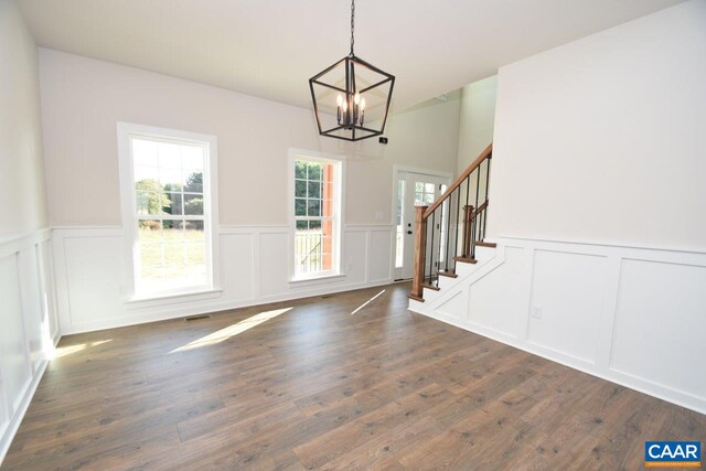 foyer entrance with an inviting chandelier, stairway, a decorative wall, and a wainscoted wall