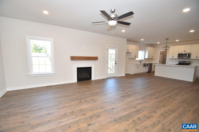 unfurnished living room featuring ceiling fan, baseboards, dark wood-type flooring, and recessed lighting