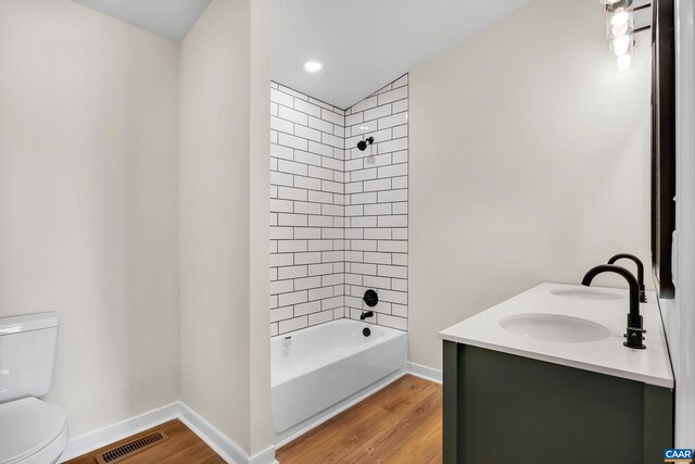 full bathroom featuring vanity, tiled shower / bath, hardwood / wood-style floors, and toilet