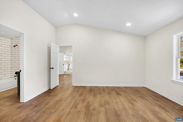 unfurnished room featuring lofted ceiling and light hardwood / wood-style flooring