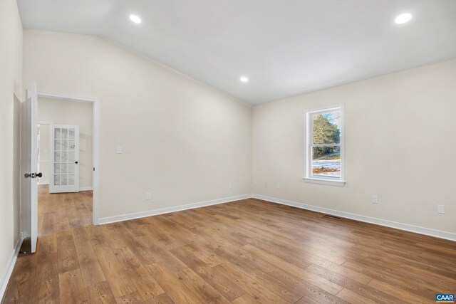 spare room featuring lofted ceiling and hardwood / wood-style floors