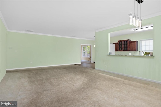 unfurnished living room with ornamental molding, plenty of natural light, baseboards, carpet flooring, and a sink