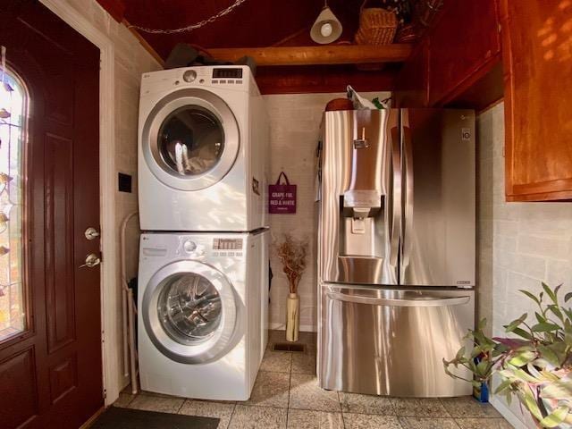 clothes washing area with laundry area, a healthy amount of sunlight, and stacked washer / drying machine