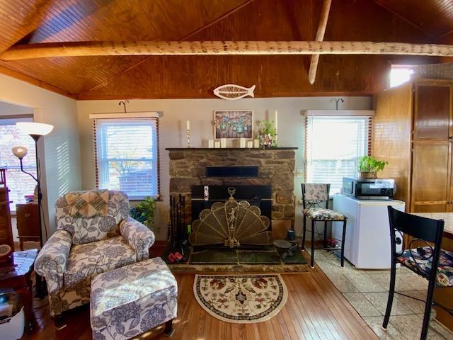 living room featuring lofted ceiling with beams, a fireplace, wood-type flooring, and wooden ceiling