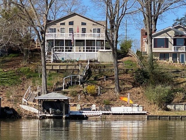 back of house with a water view, stairs, and a balcony