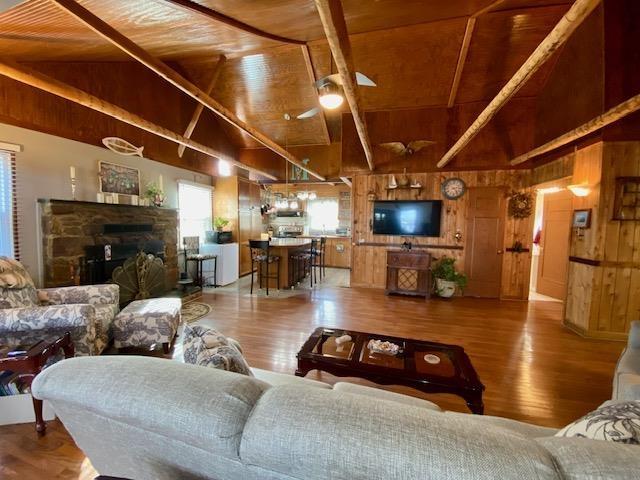 living room with wooden ceiling, wood walls, wood finished floors, and a fireplace