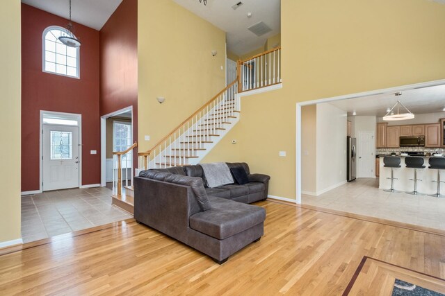 11 Tradewind Cir, Fishersville, VA 22939 - living room with light wood-type flooring, stairs, a towering ceiling, and baseboards