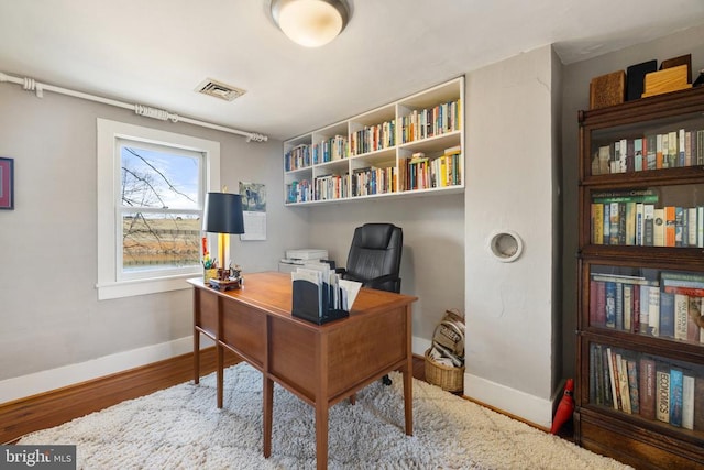 home office with baseboards and wood finished floors