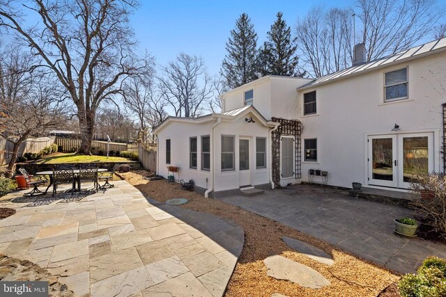 back of property with stucco siding, a standing seam roof, a patio area, outdoor dining area, and a fenced backyard
