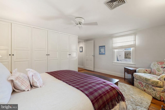 bedroom featuring wood finished floors, a closet, baseboards, and ceiling fan