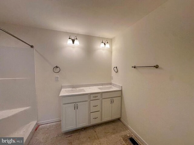 bathroom with baseboards, double vanity, and a shower