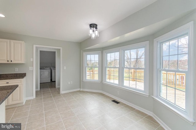unfurnished dining area featuring separate washer and dryer, baseboards, and light tile patterned flooring