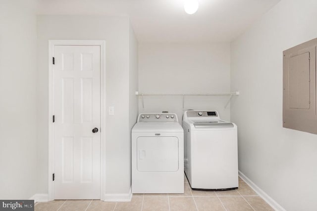 laundry room featuring electric panel, washer and dryer, light tile patterned floors, and baseboards