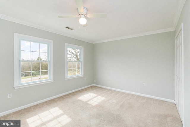 empty room featuring ornamental molding, light carpet, baseboards, and ceiling fan