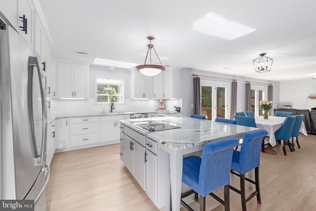 1550 Clover Dr, Fredericksburg, VA 22407 - kitchen featuring appliances with stainless steel finishes, light wood-style floors, a center island, a breakfast bar, and white cabinetry