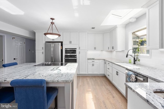 1550 Clover Dr, Fredericksburg, VA 22407 - kitchen with stainless steel appliances, light wood-type flooring, white cabinets, tasteful backsplash, and light stone counters