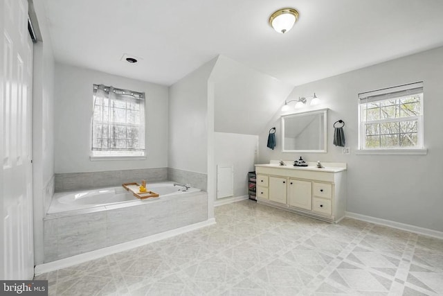 bathroom featuring baseboards, lofted ceiling, vanity, and a bath